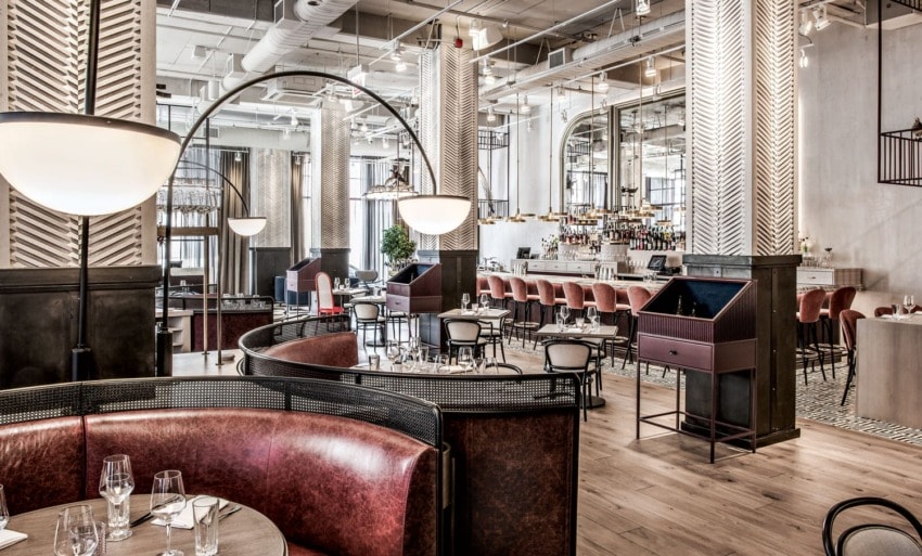 Upscale restaurant interior with modern decor, red leather seating, wooden floors, and a chic bar area.