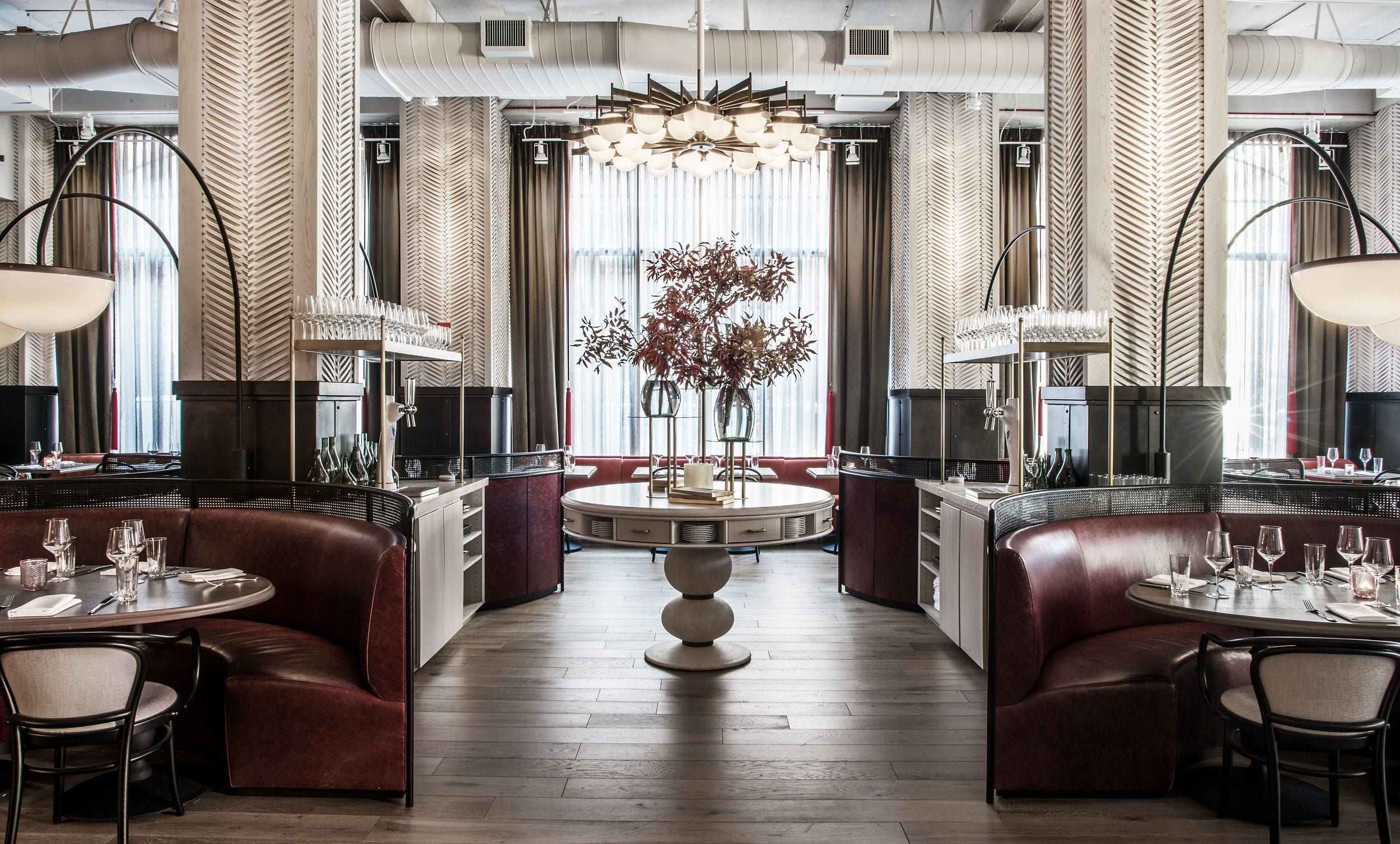 Luxurious restaurant interior with elegant round booths, a central table with floral arrangement, and modern lighting fixtures.