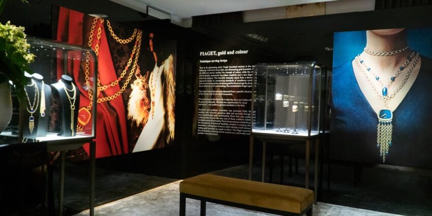Jewelry display in a dimly lit gallery with necklaces and informational panels on the walls.