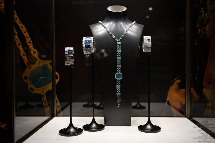 Luxury jewelry display with ornate bracelets and a necklace on black stands in a dimly lit setting.