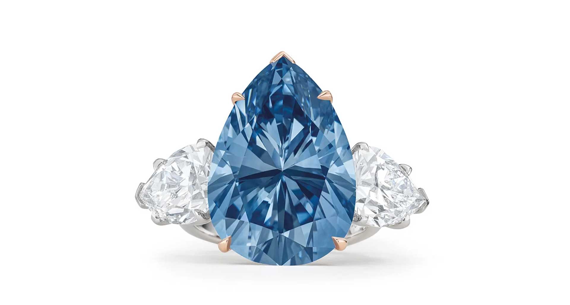 Pear-shaped blue gemstone ring with two clear side stones on a silver band