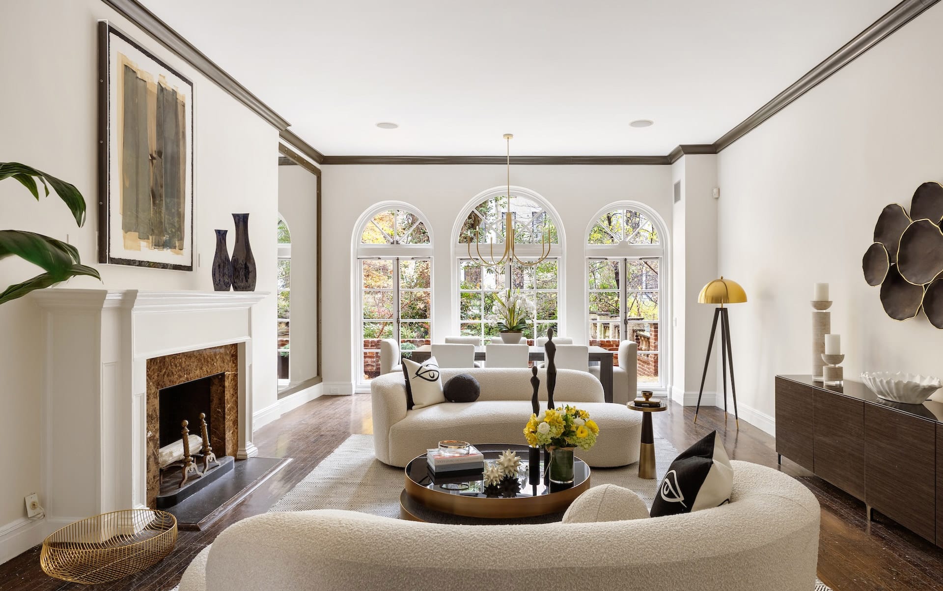 Elegant living room with arched windows, cozy sofas, a fireplace, and modern decor in neutral tones.