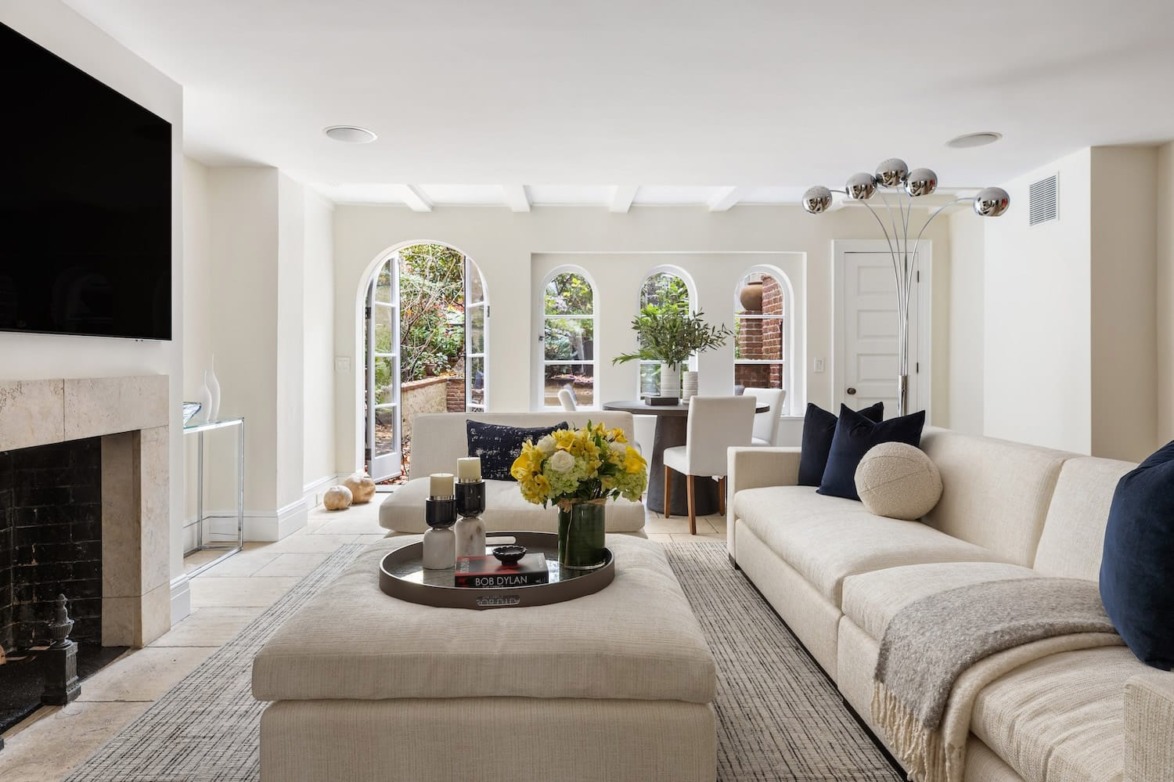 Modern living room with beige sectional sofa, large windows, round table, and fireplace.