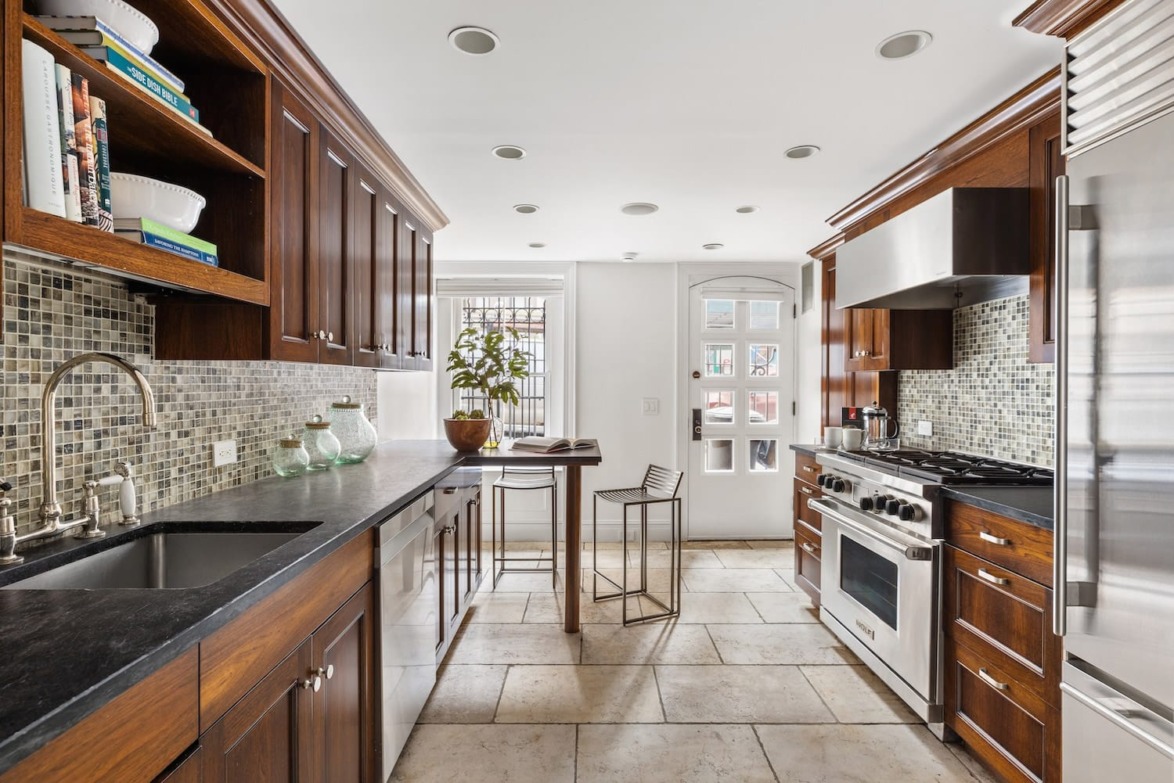Modern kitchen with dark wood cabinets, stainless steel appliances, large tile floor, and mosaic backsplash.