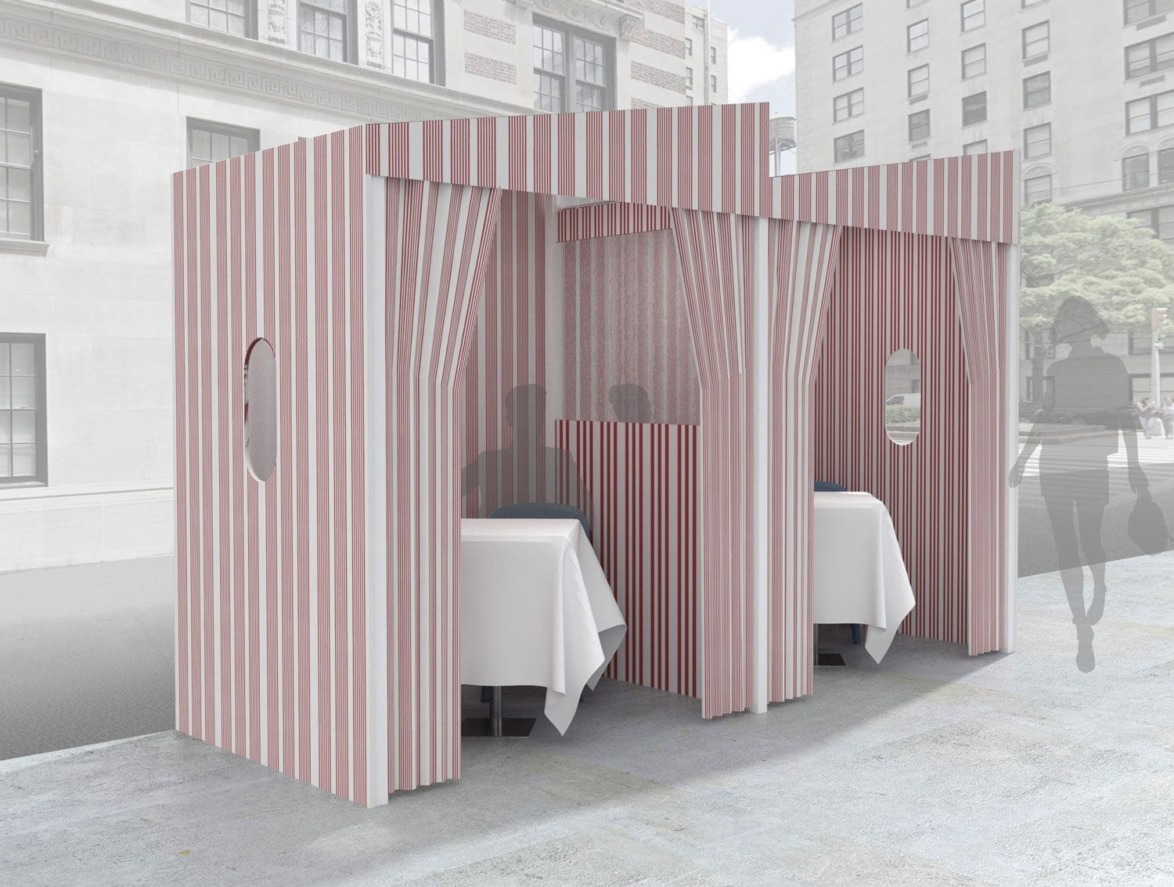 Outdoor dining booths with red and white striped fabric, each containing a table and chairs, set on a city sidewalk.