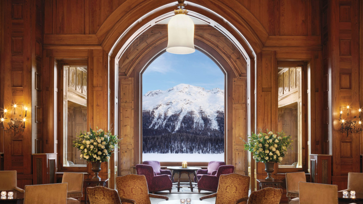 Luxurious hotel lounge with elegant furniture and large window showcasing a snowy mountain view in the background.