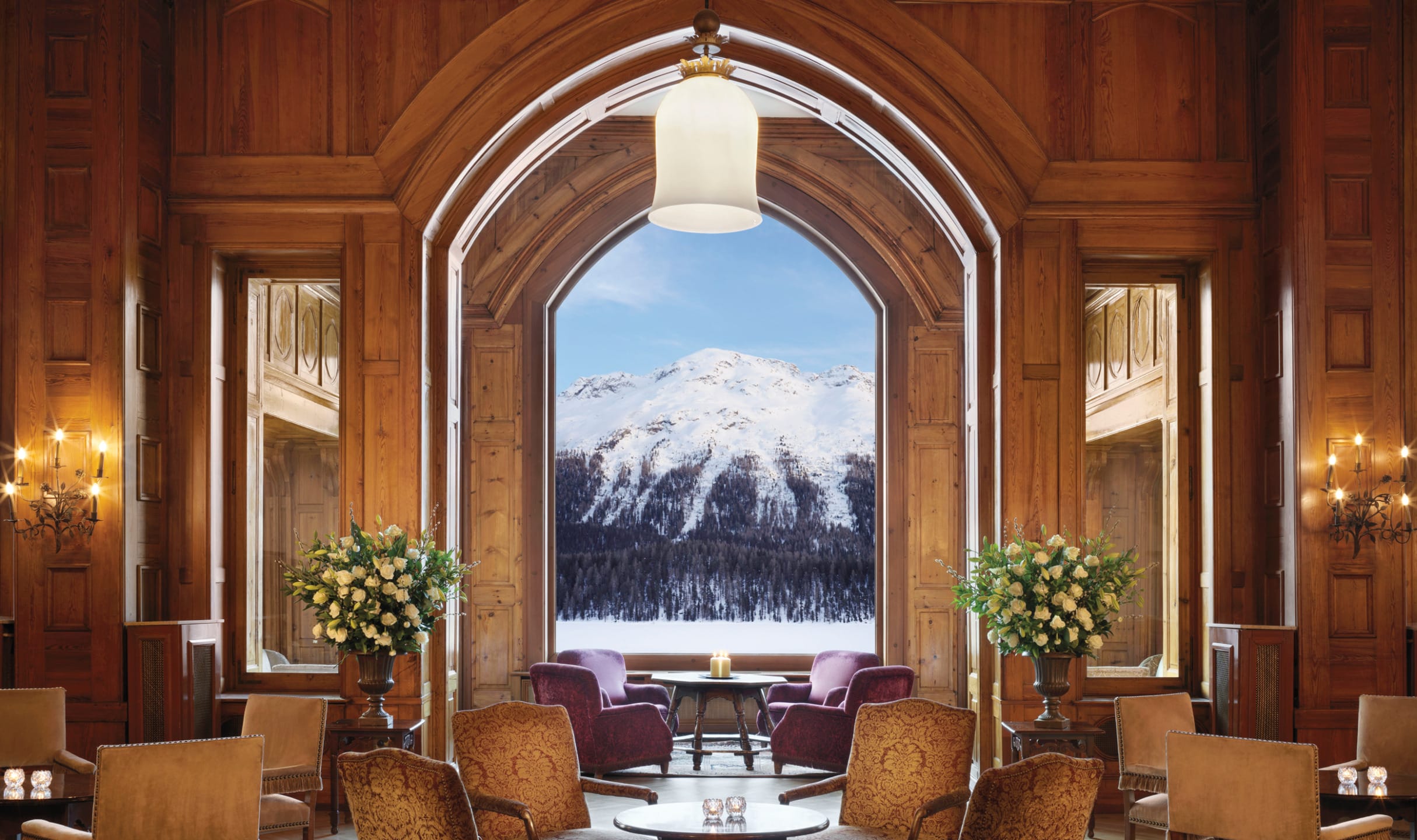 Luxurious hotel lounge with elegant furniture and large window showcasing a snowy mountain view in the background.