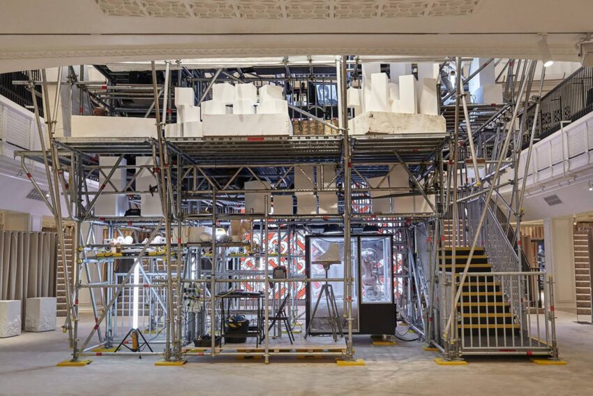 Scaffolding structure inside a spacious building lobby with modern architectural elements and various equipment.