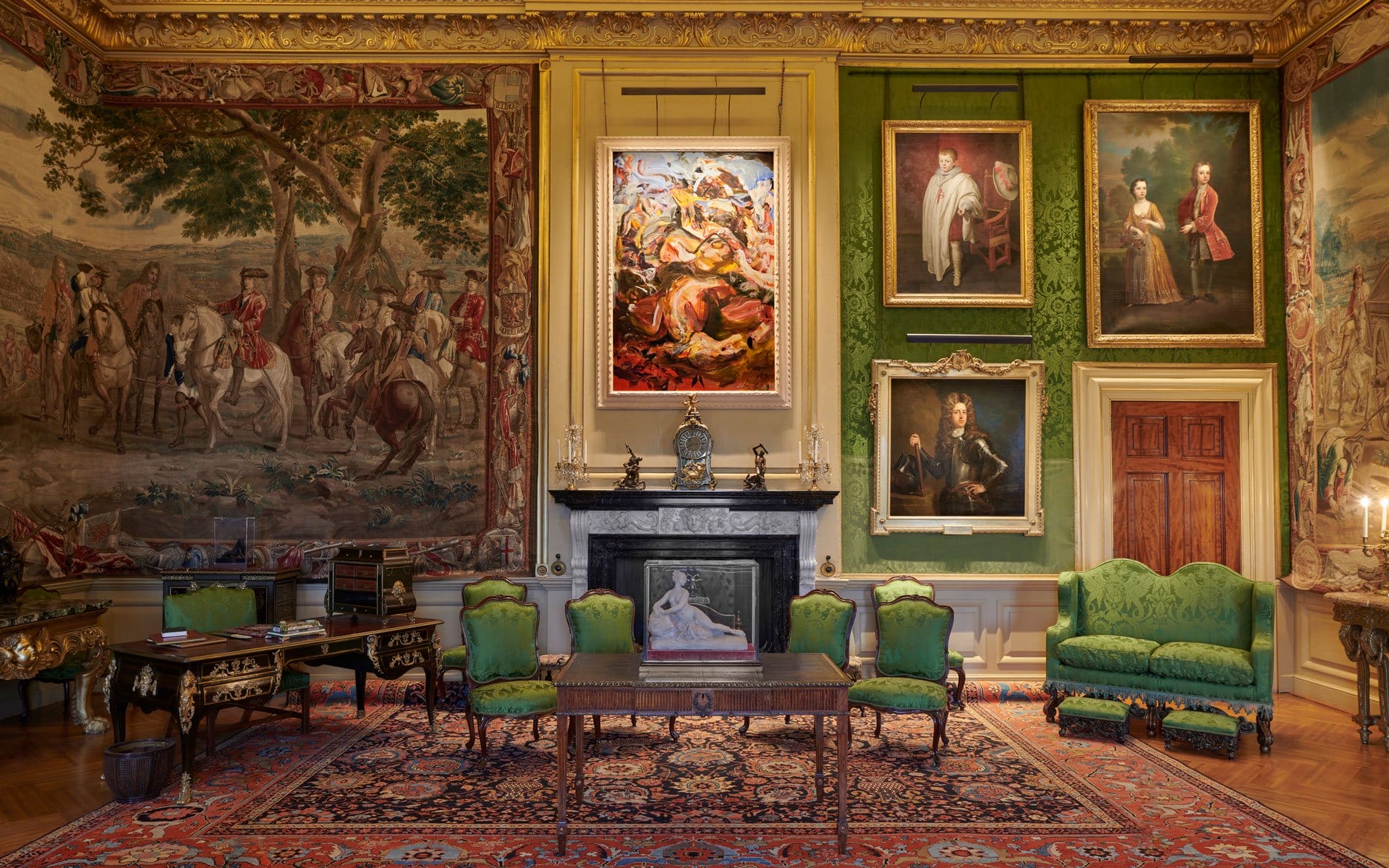 Luxurious room with green furniture, ornate paintings and tapestries, intricate ceiling, and a richly decorated carpet.