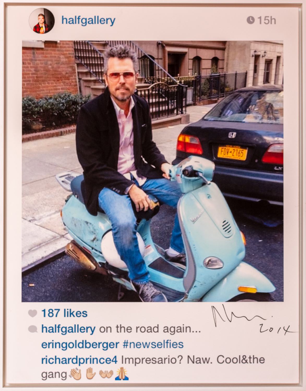 Person sitting on a blue scooter parked on a city street, wearing sunglasses and a jacket.