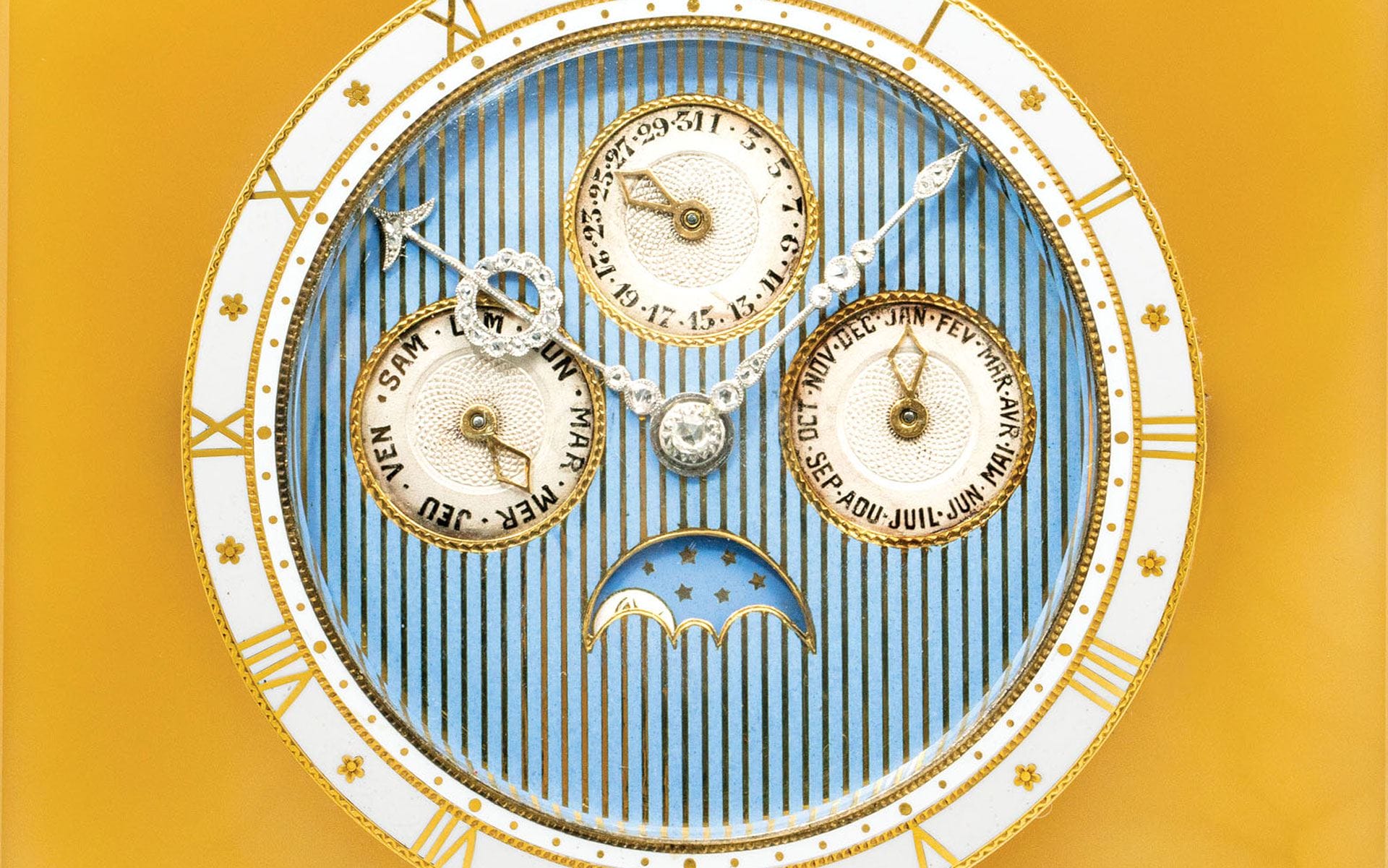 Close-up of a vintage watch face displaying time, day, date, and month against a yellow and blue background with decorative patterns