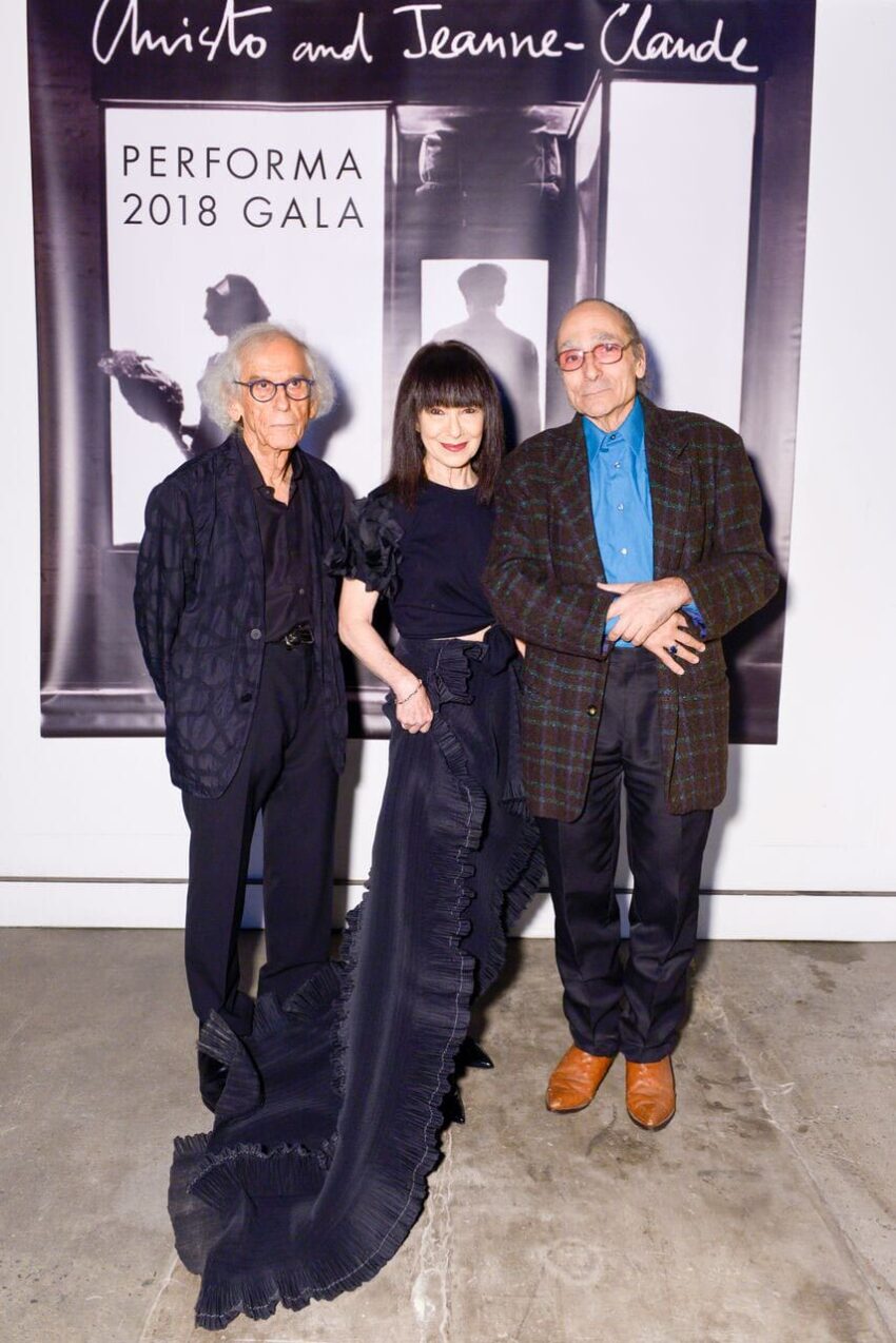 Three people standing in front of a Performa 2018 Gala poster with an elegant black dress and casual suits.