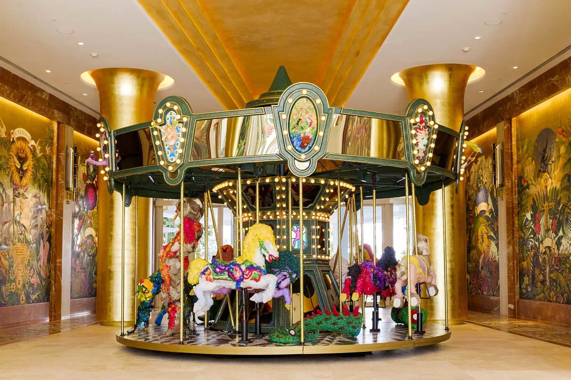Colorful indoor carousel with animal figures in a luxurious golden setting.