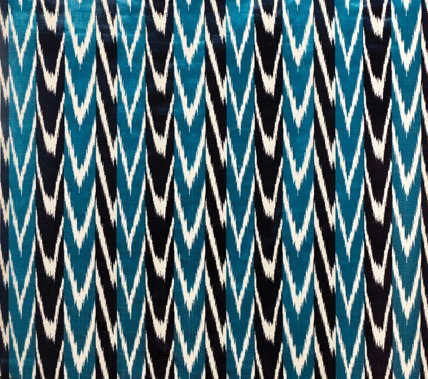 Blue, black, and white zigzag ikat pattern textile with a repetitive geometric design.