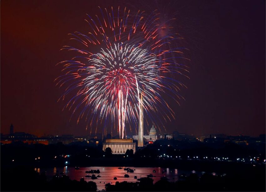 Fireworks exploding over the Washington Monument and Lincoln Memorial, illuminating the night sky with vibrant colors.