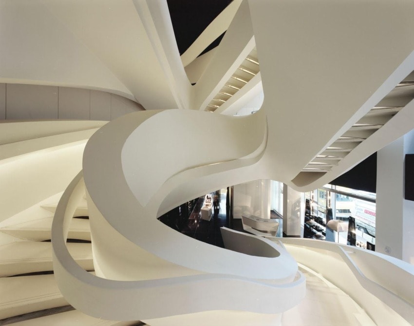 Futuristic white spiral staircase with smooth curves in modern architectural space, featuring large windows and sleek design.