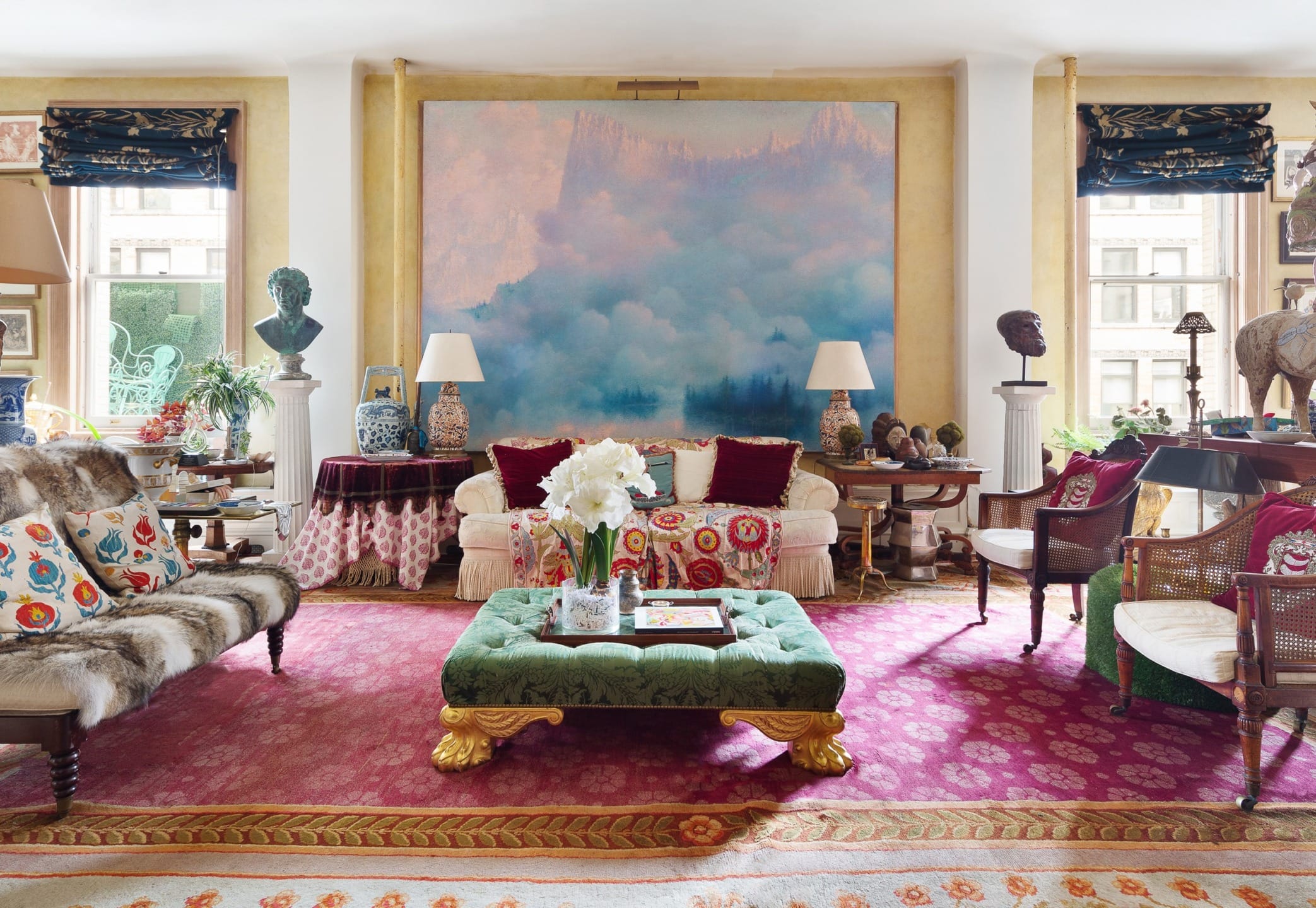 Eclectic living room with colorful rugs, ornate furniture, large abstract painting, and various decorative sculptures.