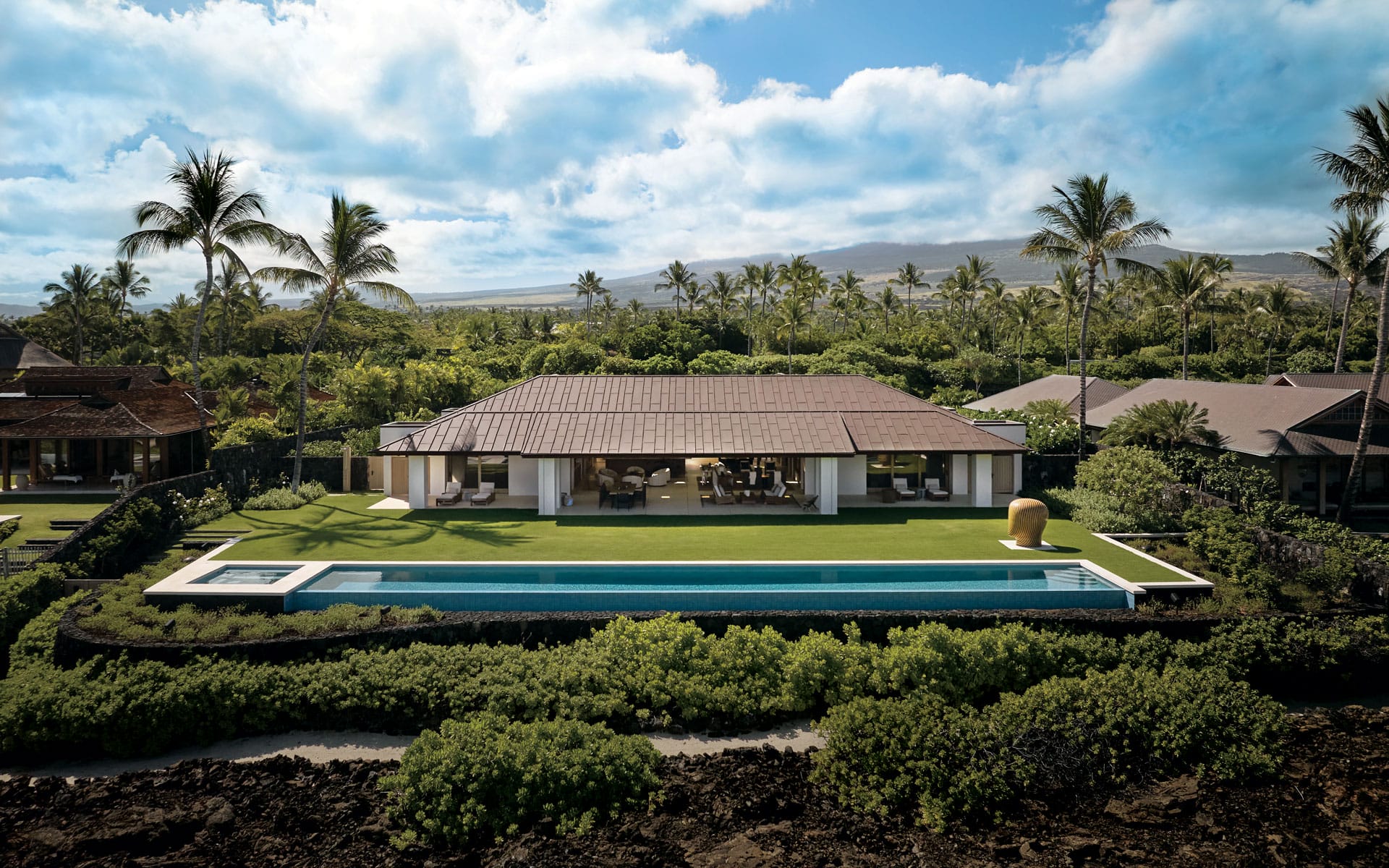 With interiors masterminded by Nicole Hollis, the beachfront residence in the Hawaiian community of Kukio is composed of three structures, with the rear of the main house opening up to a lawn and an infinity pool looking out to the ocean beyond. Noted architect John Hara designed the home, with architectural firm Walker Warner undertaking modest structural updates and gardens by Jay Warner Landscape Architecture.