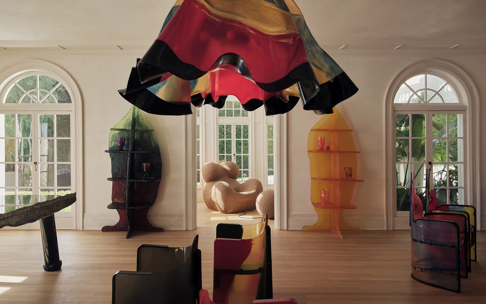 Colorful modern living room with abstract furniture, large windows, and unique chandelier, featuring vibrant art pieces.