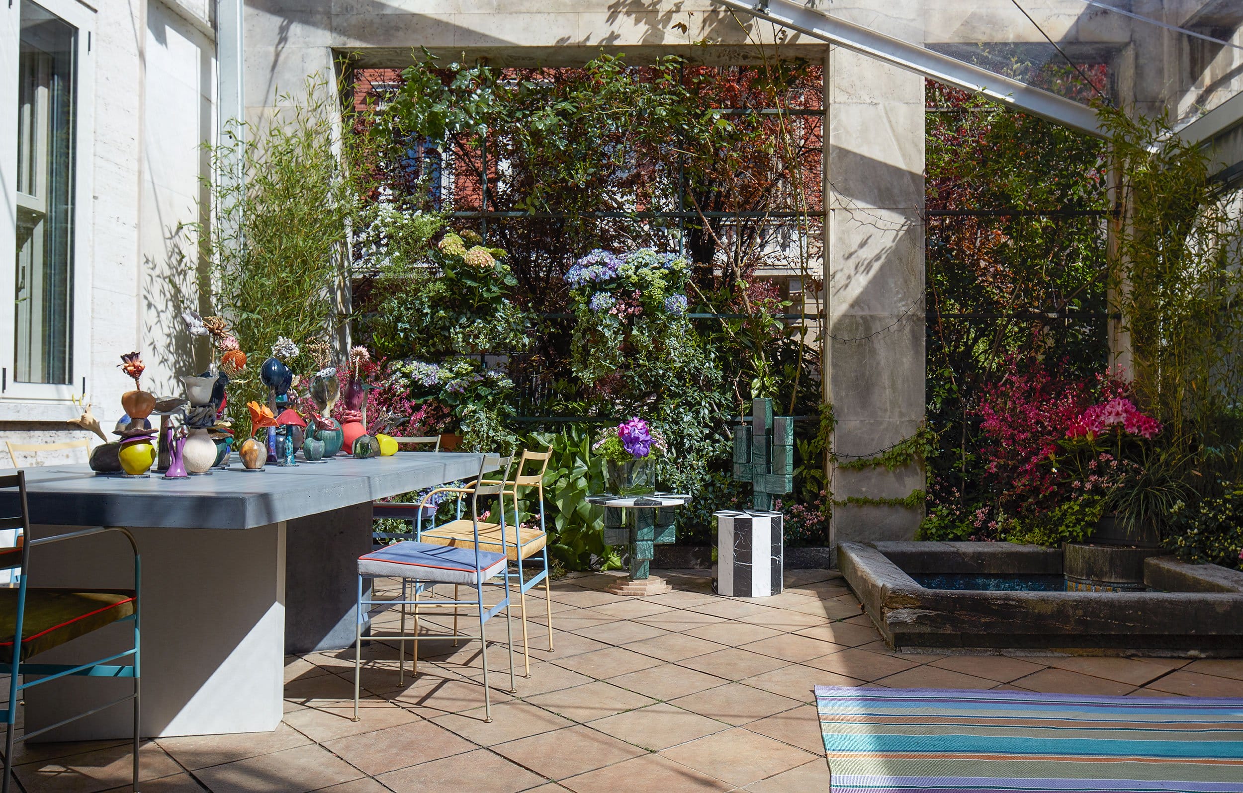 Colorful outdoor patio with a dining table, chairs, and a lush vertical garden under sunlight.