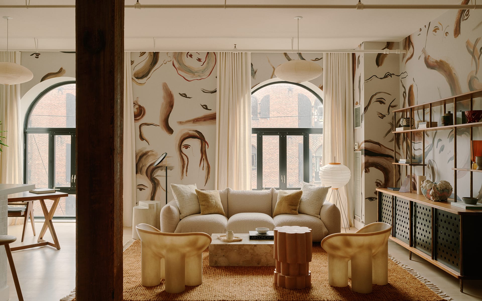 Stylish living room with artistic wallpaper, modern furniture, and large arched windows providing natural light.