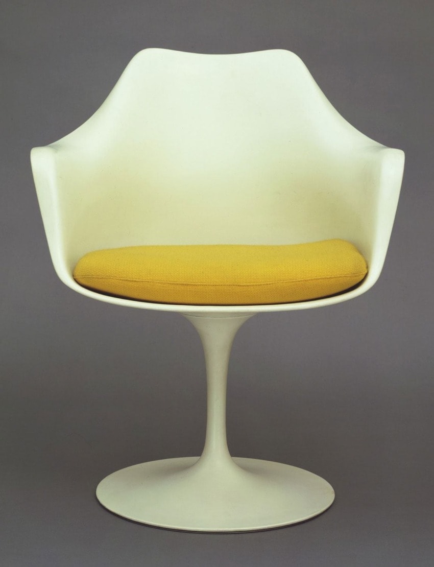 White modern chair with a yellow cushion on a pedestal base against a gray background.