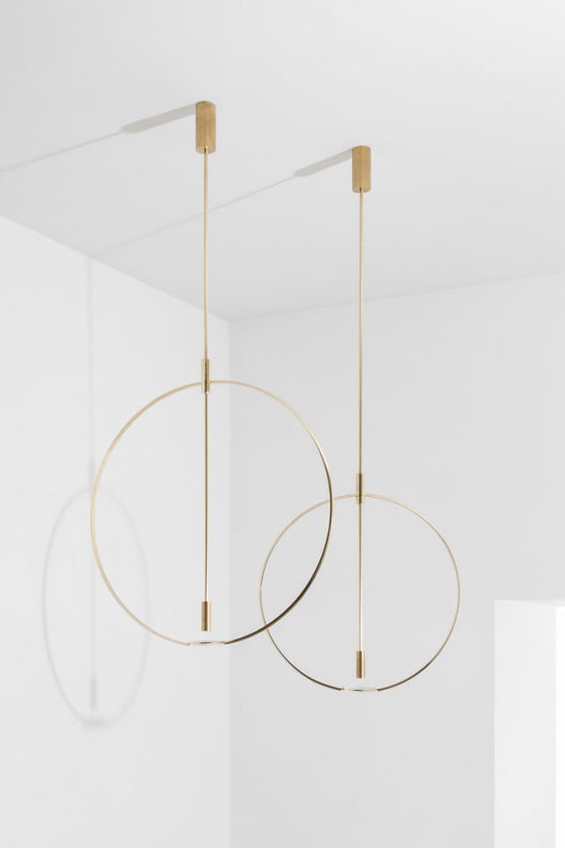 Minimalist gold pendant lights with circular design hanging from a white ceiling.