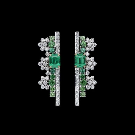 Emerald and diamond earrings with floral design on a black background