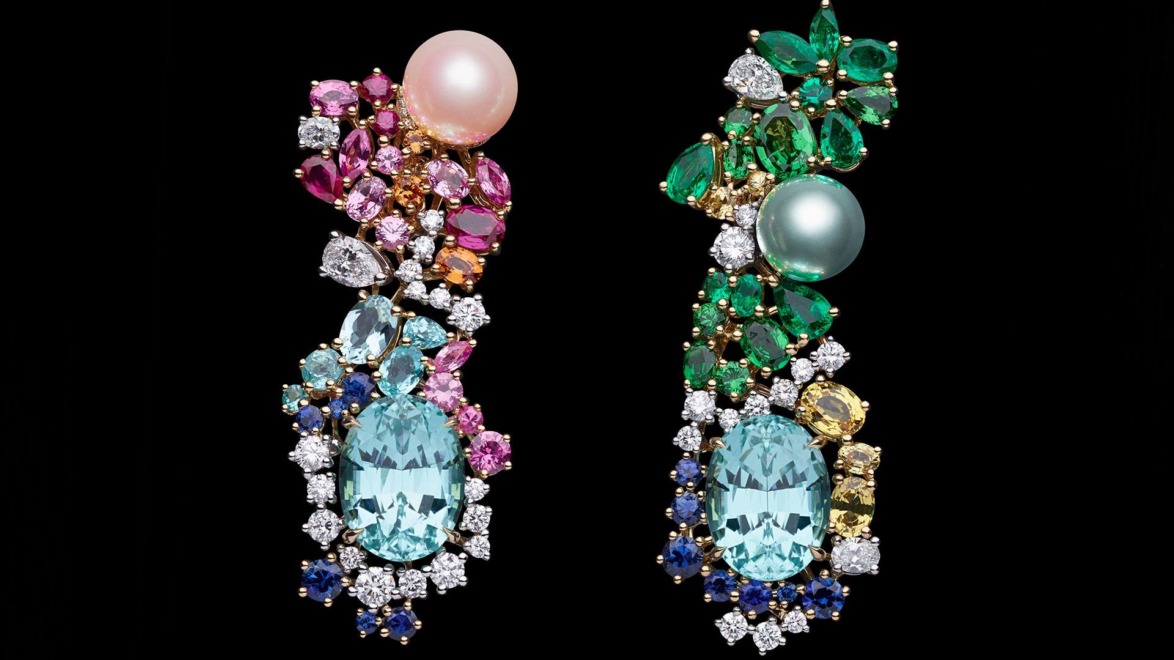 Colorful ornate earrings with gemstones like pearls, emeralds, sapphires, and diamonds against a black background.