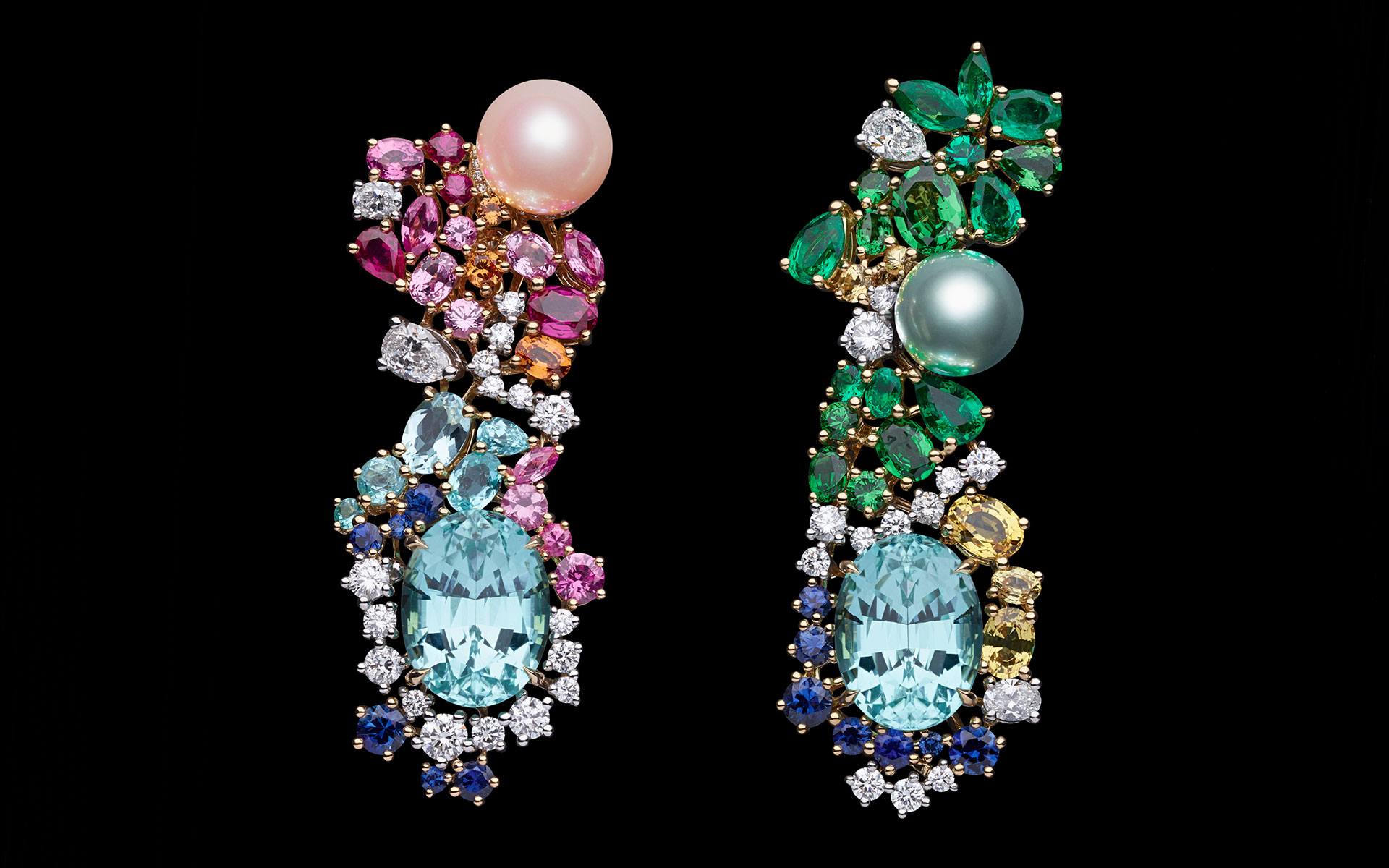 Colorful ornate earrings with gemstones like pearls, emeralds, sapphires, and diamonds against a black background.