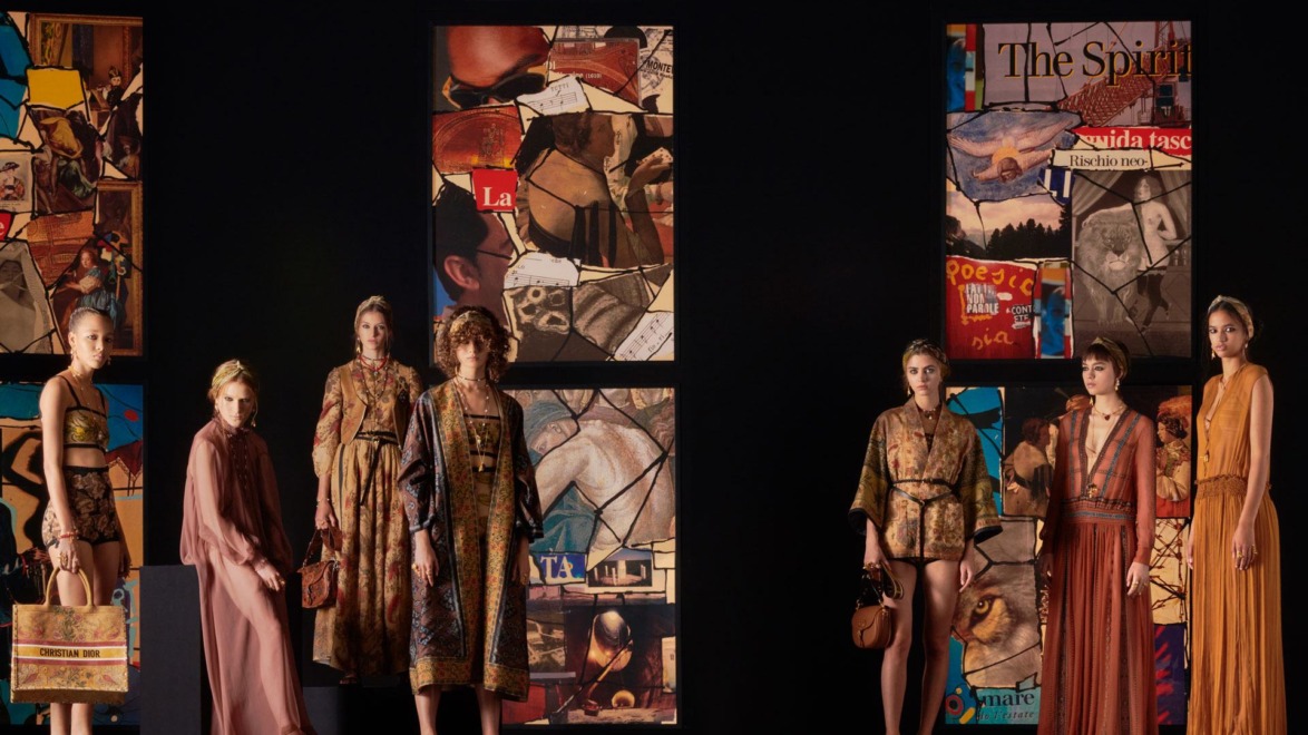 Fashion models on a runway showcasing vibrant and artistic outfits against a backdrop of colorful abstract panels.