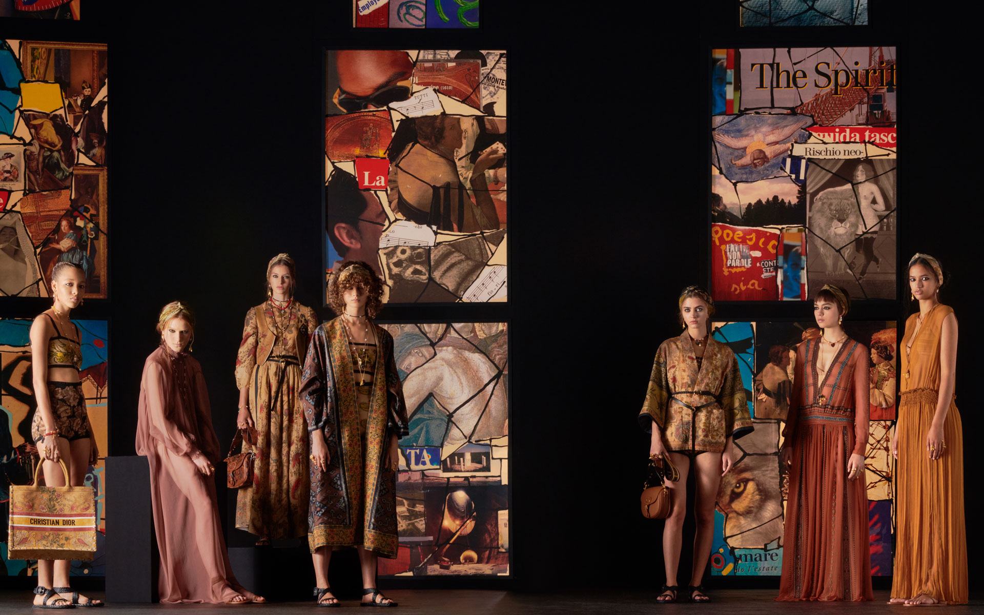 Fashion models on a runway showcasing vibrant and artistic outfits against a backdrop of colorful abstract panels.