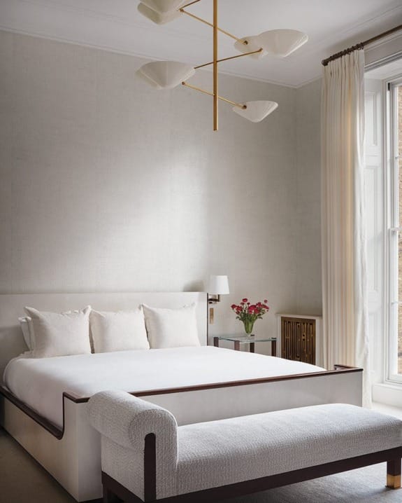 A vintage Italian chandelier spirals above the primary bedroom's bespoke parchment-clad bed.