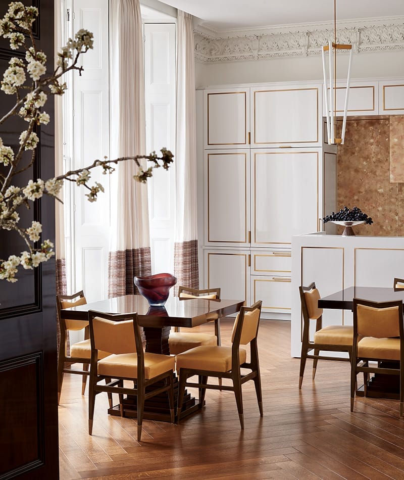 In the dining area near the open kitchen, Kleinberg installed a pair of custom pedestal tables and lacquered mahogany chairs beneath a pendant by Michael Anastassiades.