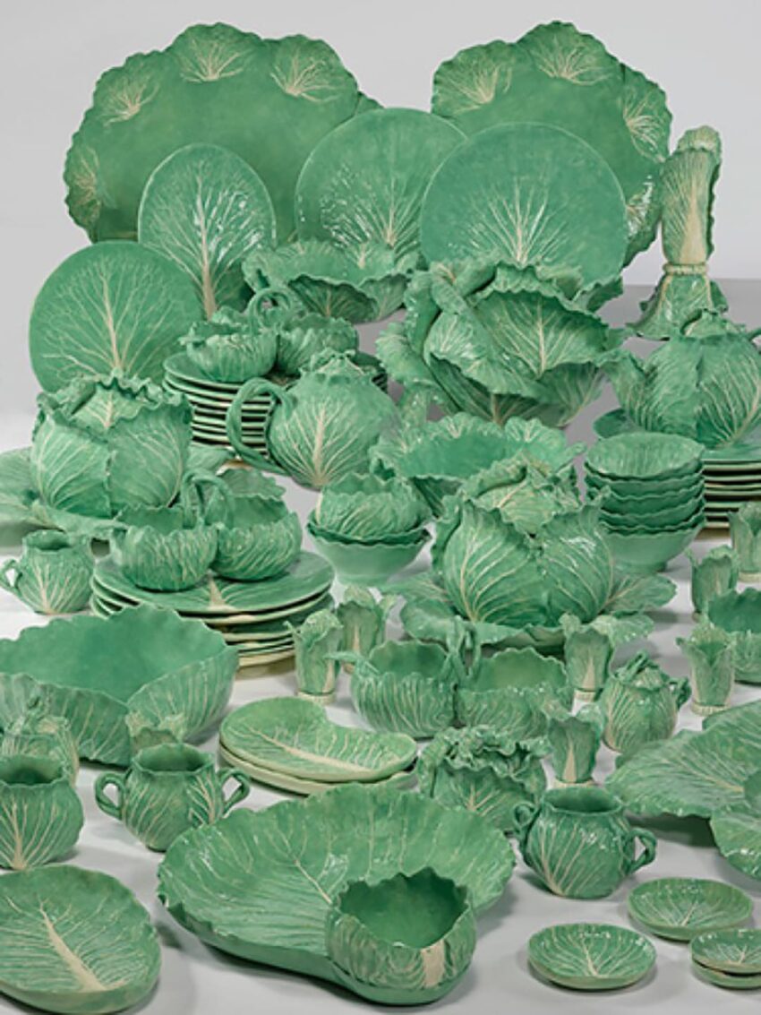 green ceramic dinnerware set designed to resemble cabbage leaves with various plates, bowls, and serving pieces displayed