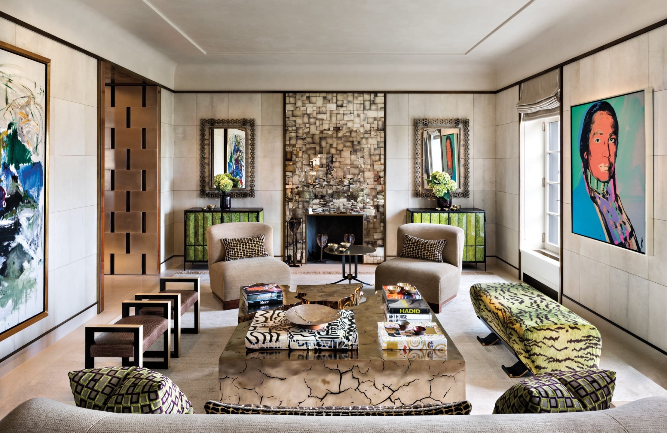 Modern living room with eclectic art, patterned furniture, and a central coffee table surrounded by plush seating and vibrant decor.