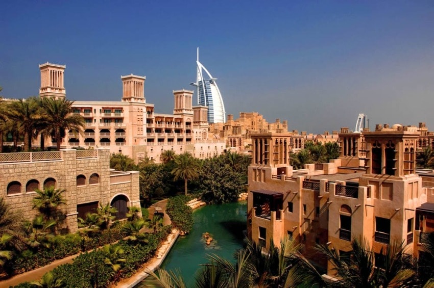 Scenic view of traditional Middle Eastern architecture and modern skyscraper in Dubai under a clear blue sky.