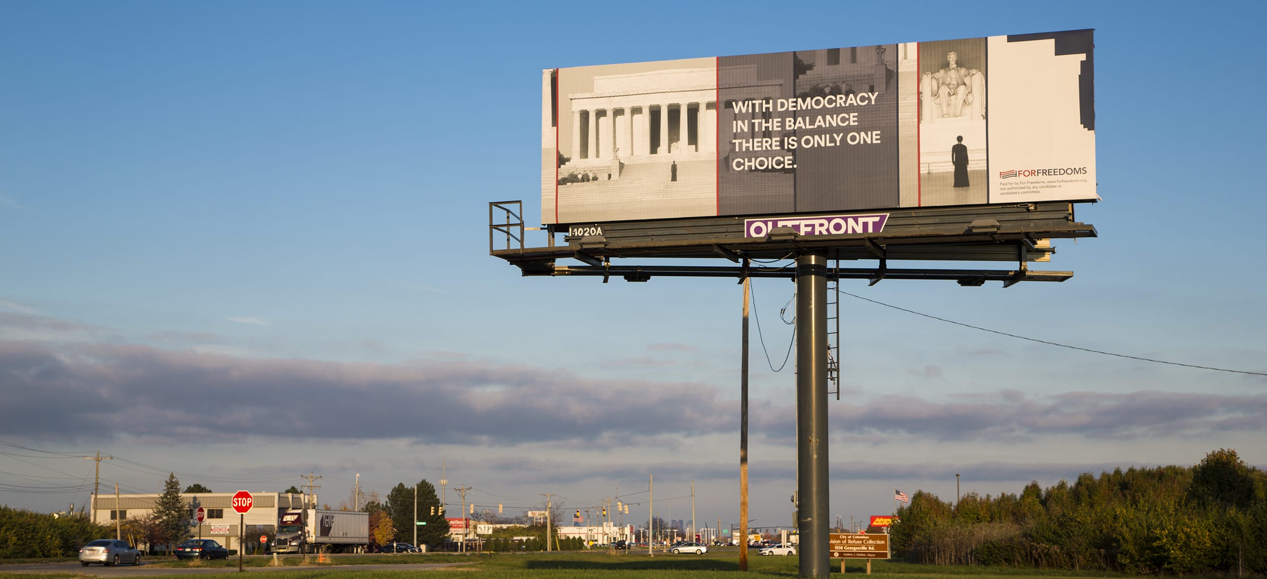Billboard on roadside with message about democracy balance, featuring an image of a courthouse and a statue of blindfolded lady justice.