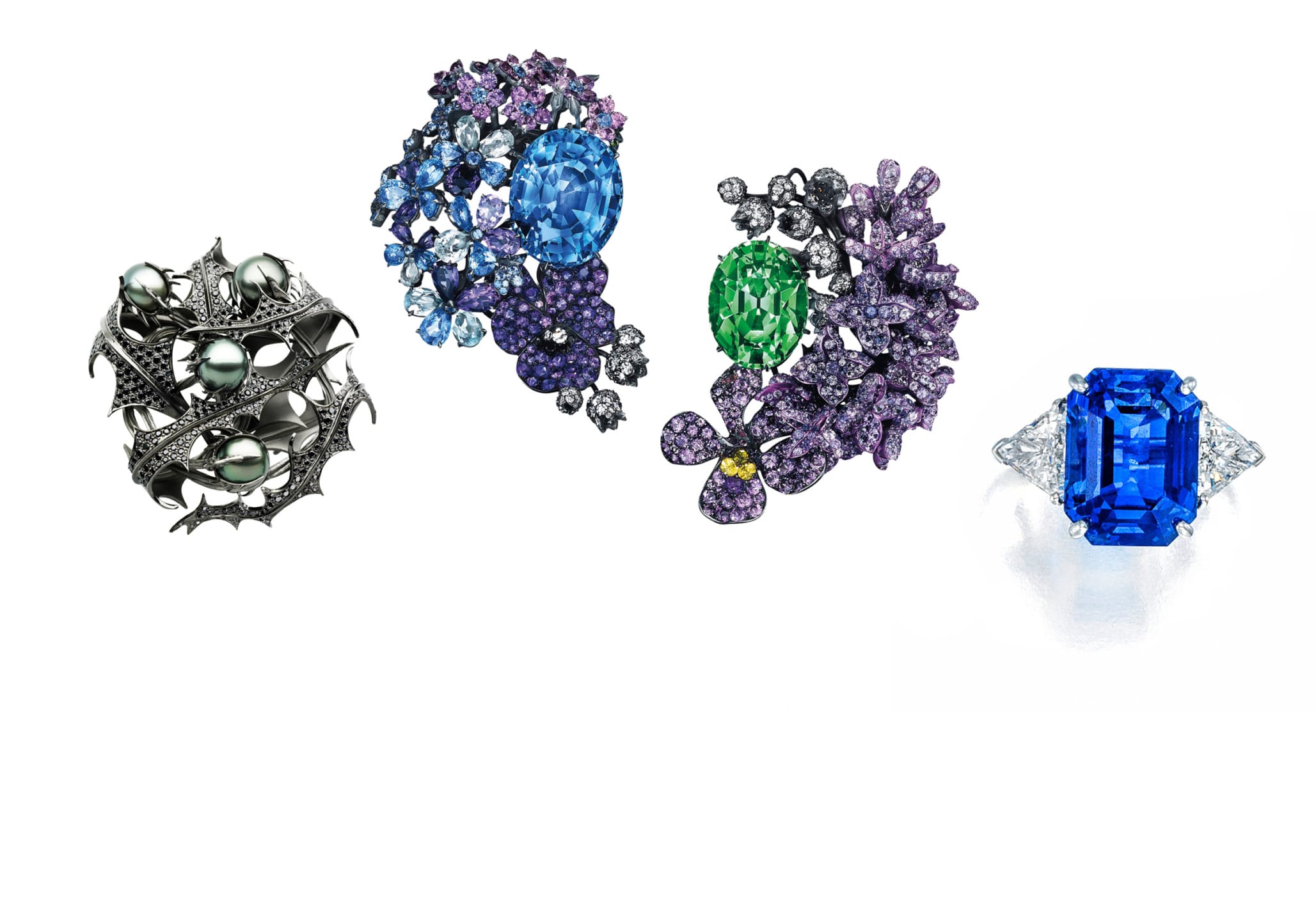 Four ornate jewelry pieces with colorful gemstones, including blue and green stones, set in intricate designs.