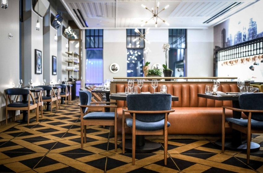 Modern restaurant interior with elegant furniture, geometric-patterned floor, and a warm ambient lighting setup.