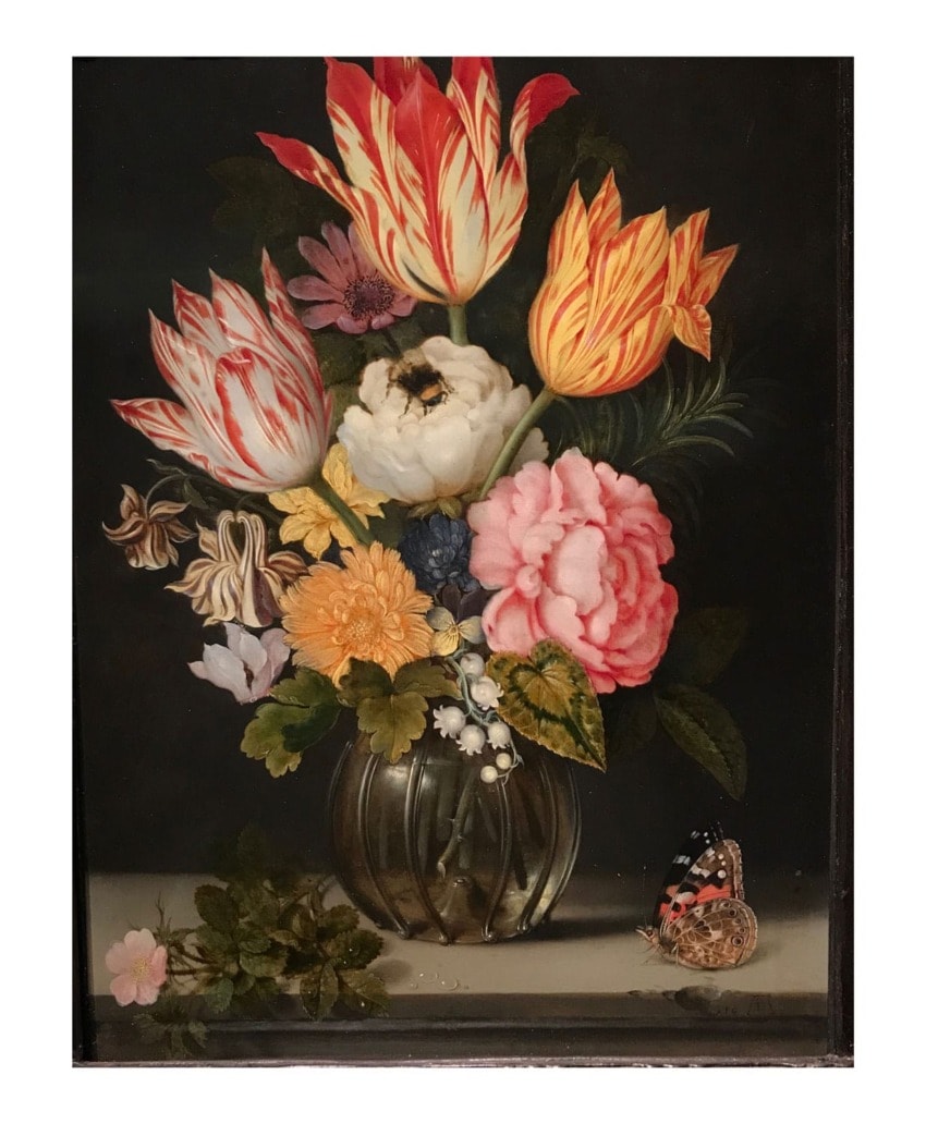 Still life painting of vibrant tulips, roses, and other flowers in a vase with a butterfly and small decorative elements.