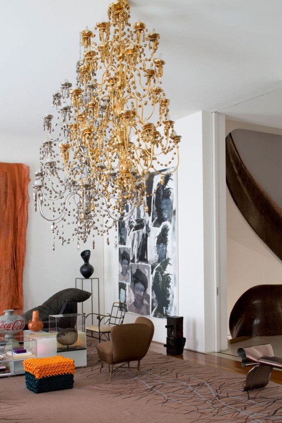 Luxurious living room with ornate gold chandelier, modern art, and eclectic furniture.