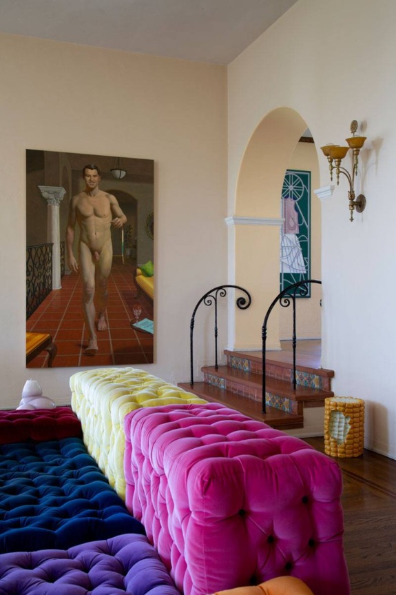 Colorful tufted sofas in a living room with an archway, decorative railing, and a large painting on the wall.