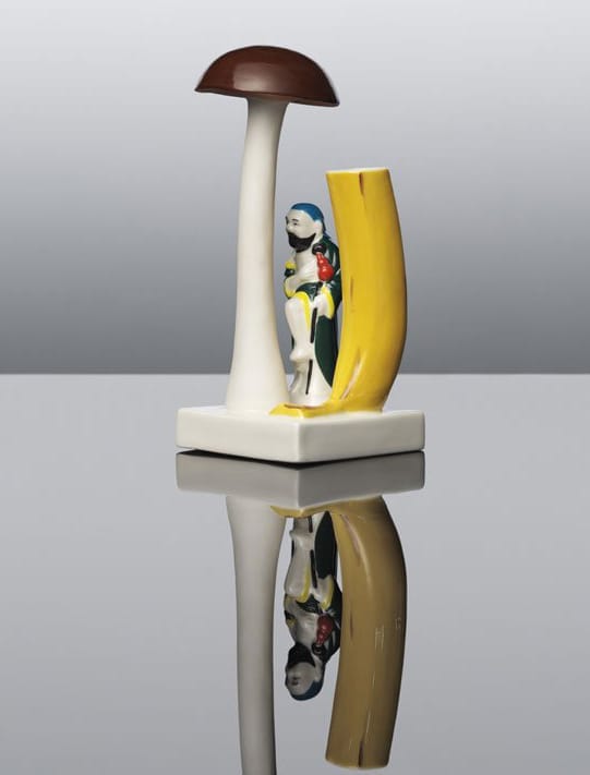 Surreal ceramic sculpture featuring a tall mushroom and abstract human figure against a mirrored surface.