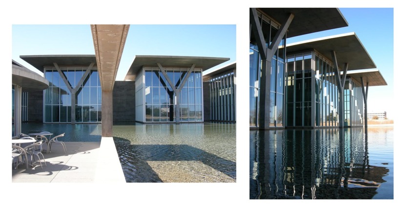 Modern building with large glass windows and concrete overhanging roofs reflecting on the calm water surface below.