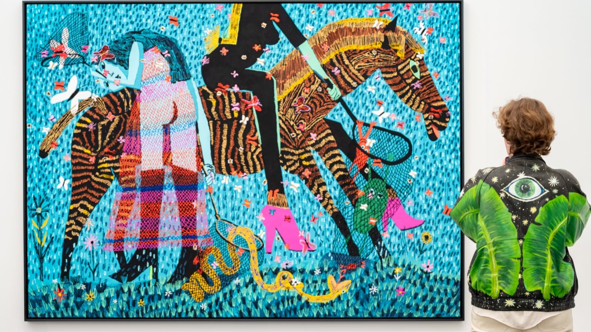 Person in detailed jacket looking at vibrant painting at Frieze