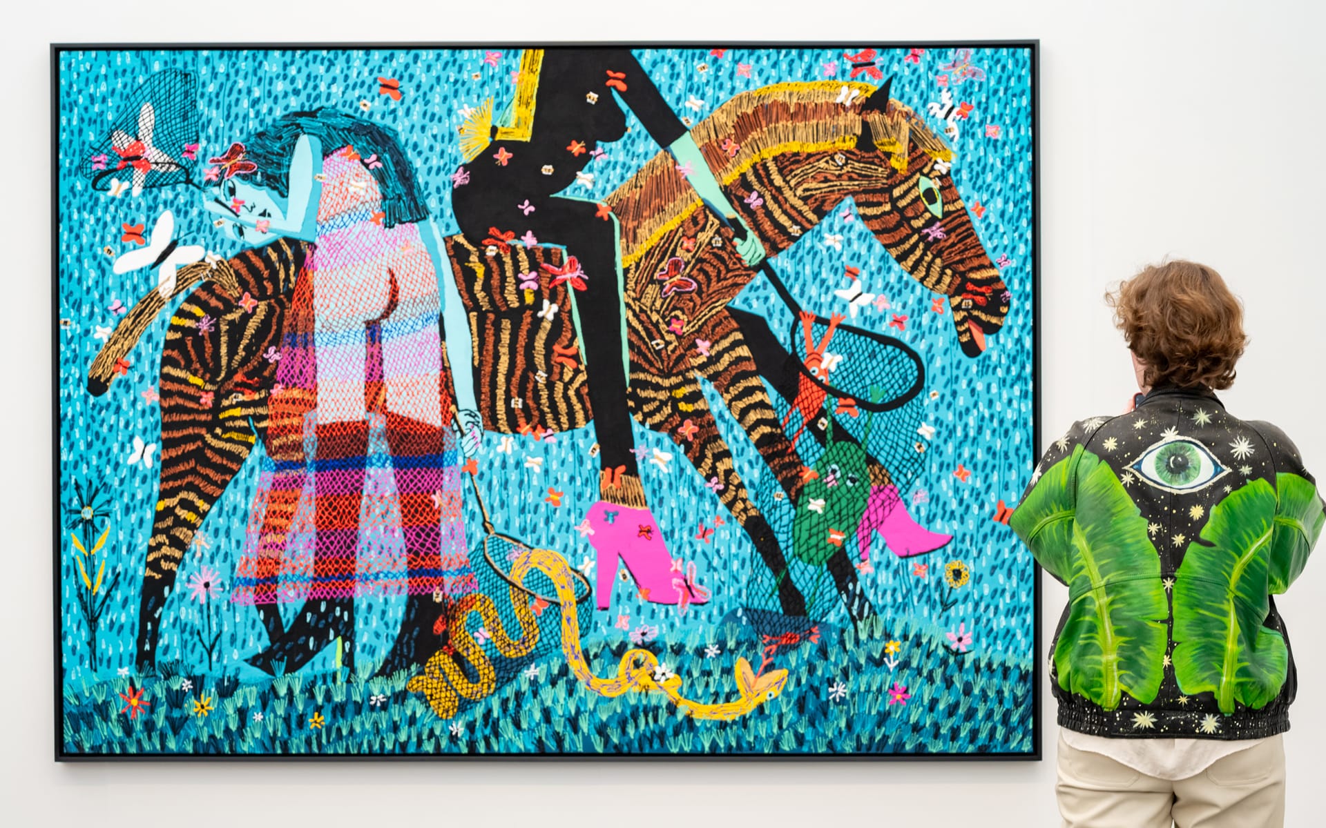 Person in detailed jacket looking at vibrant painting at Frieze