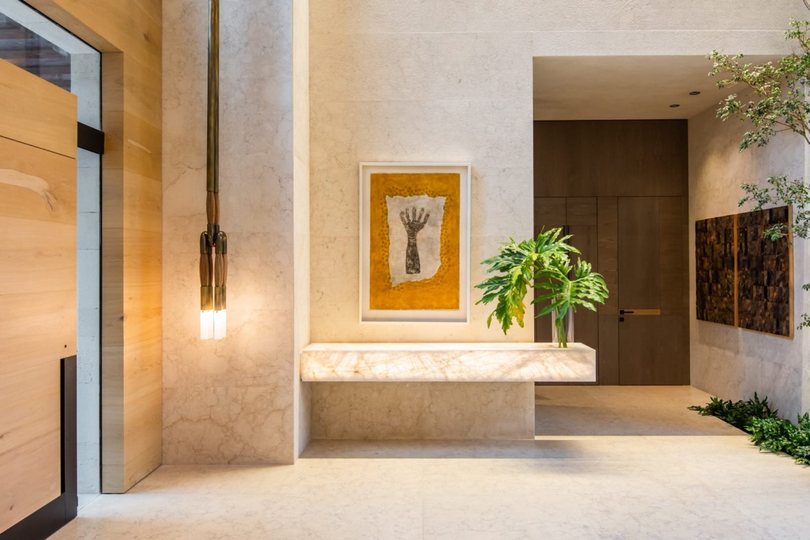 Modern hallway with a large artwork on the wall, minimalist decor, pendant lights, plants, and neutral tones.