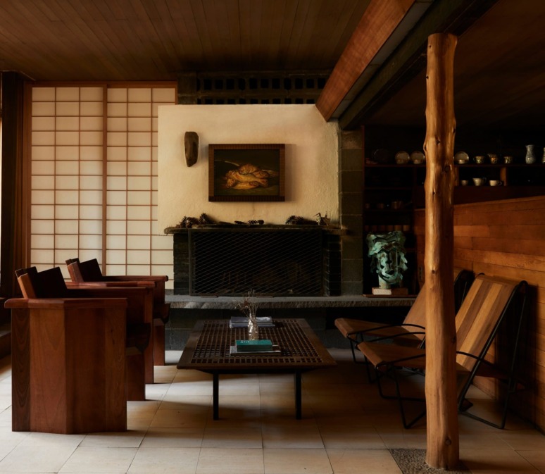 Mid-century modern living room with wooden furniture, fireplace, artwork, and decorative shelves.