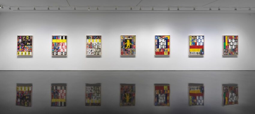 Art gallery with colorful framed paintings on a white wall and their reflections on the shiny black floor.